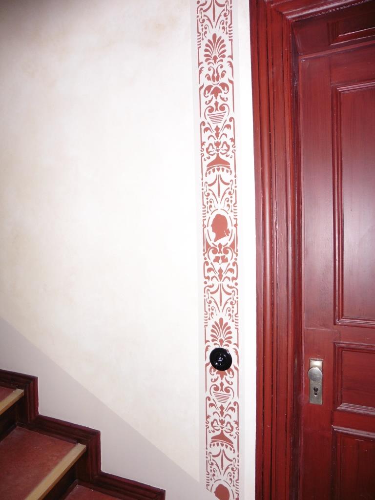 In einer Remise am Denkmal in Berlin Charlottenburg Wurden die Wände und Türen mit einer Patina überarbeiten. An den Wandflächen ist eine Technik zum Einsatz gekommen, die an eine vereinfachte Marmorimitation oder Marmormalerei erinnert. Die Patina schützt wände vor Beschädigungen besser als eine herkömmliche Dispersionsfarbe. Durch die Patina nimmt man Verunreinigungen durch das Changieren nicht so schnell war. Die historische Schablonierung als sekkant aus der Gründerzeit spiegelt den Zustand der Erbauungszeit wieder und soll das schmale Treppenhaus gliedern. An den Türflächen wurde auch eine Patina aufgesetzt. Diese wird im Duktus einer Holzimitation oder Holzmalerei aufgebracht. Auch hier nimmt man Verunreinigungen und Beschädigungen durch die Changieren der Lasur nicht so schnell war. Auch sehen sich Unebenheiten in der Tür weck. Diese Techniken waren ursprünglich Aufgaben des Maler und Malermeister. Heute werden solche Aufgaben nimmermehr vom Restaurator ausgeführt. Norbert Schimpf der Maler, Malermeister, staatlich geprüfter Techniker für Farb- und Lacktechnik und Restaurator im Handwerk ist, führt mit seinen Gesellen solche Arbeiten aus.